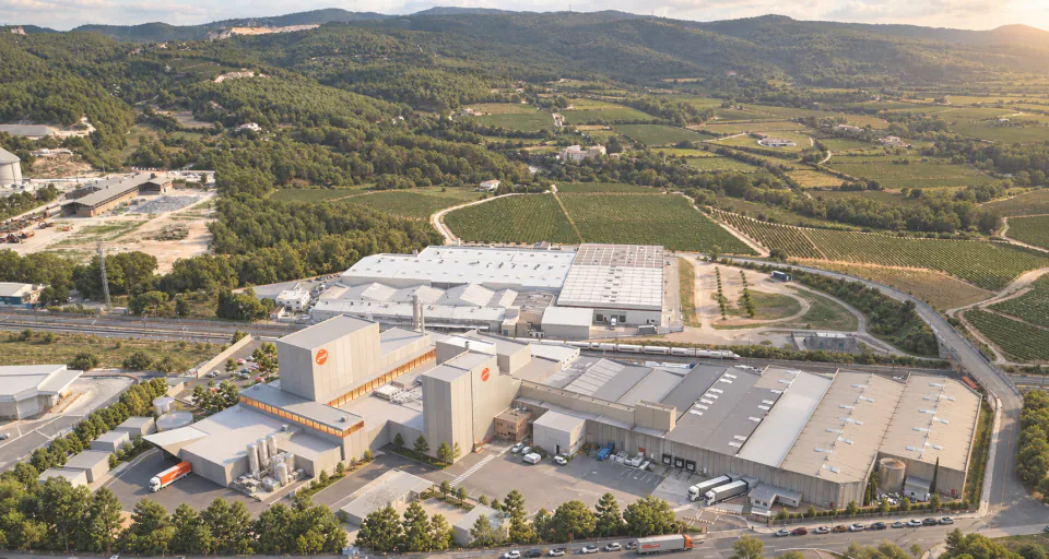 Aerial view of the factory complex among vineyards and wooded hills