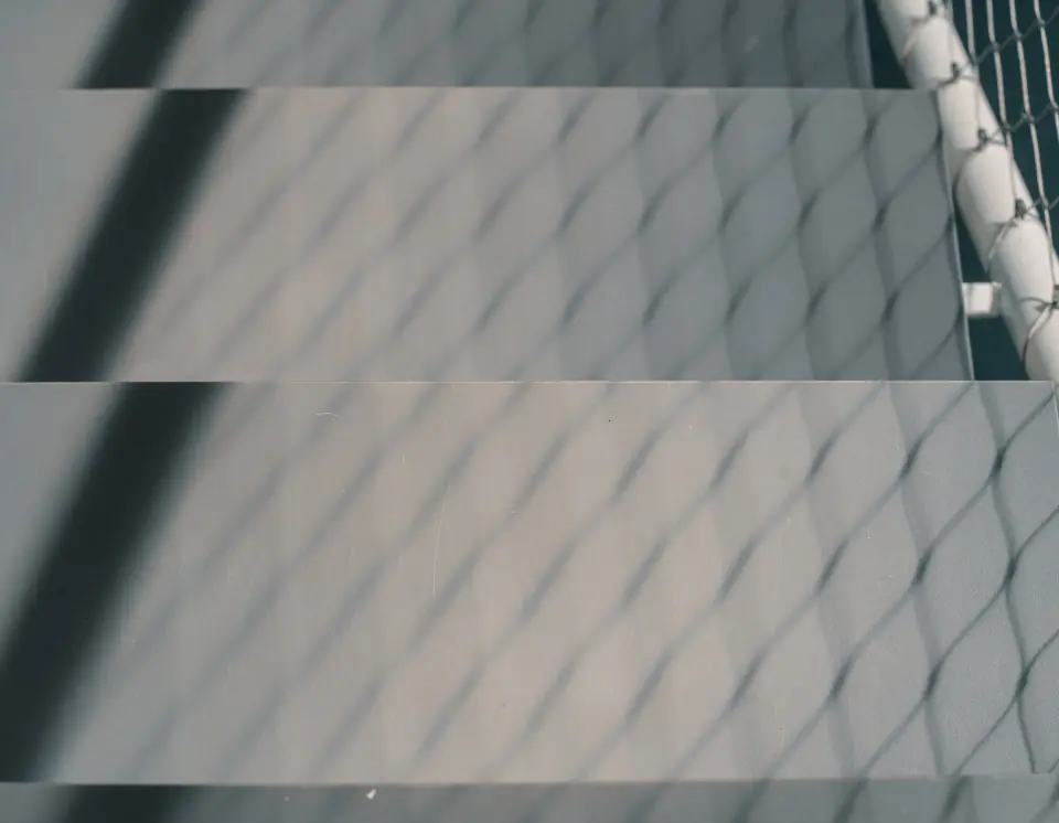 Shadows of a metal mesh balustrade falling across the stairs