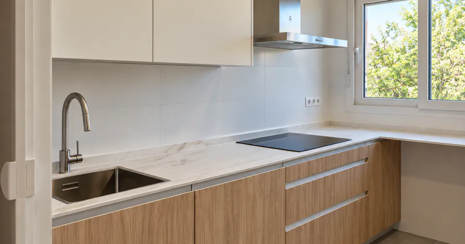 Kitchen with white worktops, oak units and a window onto the trees