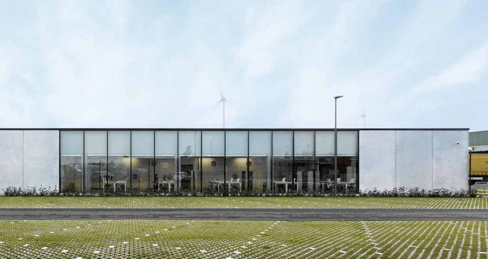 Long, low glazed laboratory and office building behind a grass-paved car park