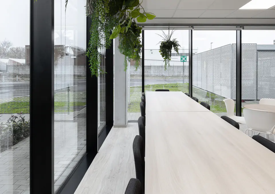 Glazed corridor with hanging plants and a long timber bench